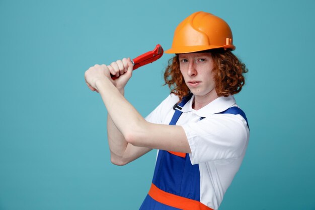 seguro joven constructor hombre en uniforme con llave de gas aislado sobre fondo azul.