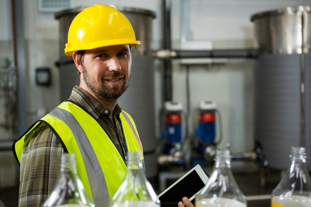 Seguro trabajador varón sosteniendo tableta digital en la fábrica.