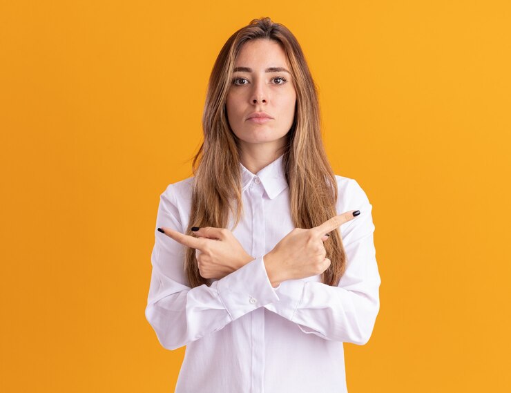 Foto gratuito seguros de joven bastante caucásica apunta a los lados aislados en la pared naranja con espacio de copia