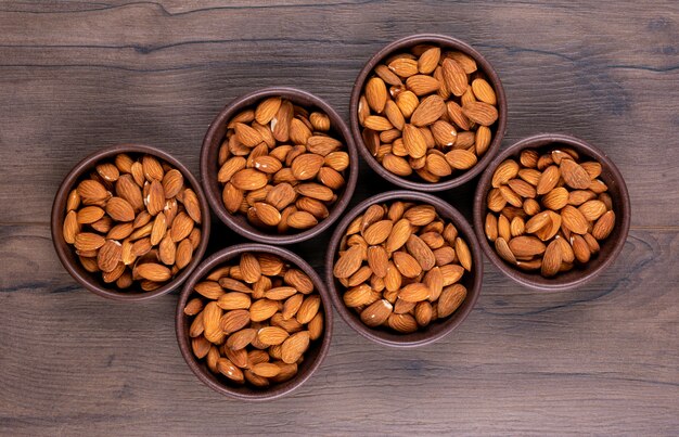 Seis cuencos de almendras en la mesa de madera, vista superior.