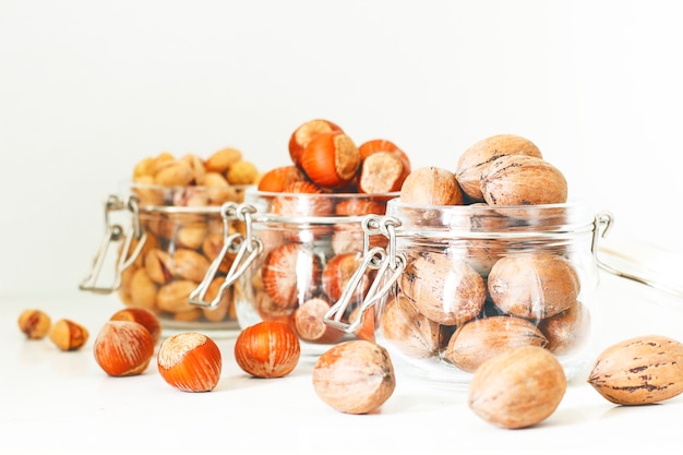 Selección de varias nueces: avellanas, pistachos y nueces en frascos de vidrio.