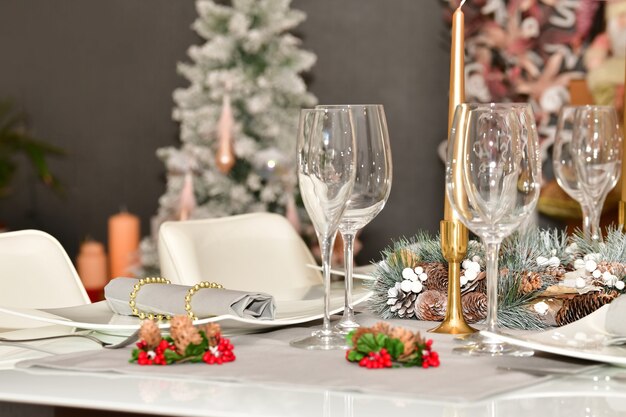 Seleccione el enfoque de una mesa con vasos, una corona de piñas y otra decoración navideña.