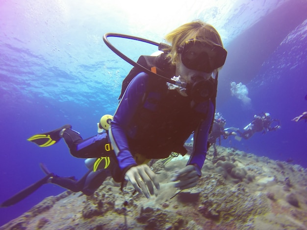 Selfie buceo submarino disparó con selfie stick. Profundo mar azul. Gran angular disparo.