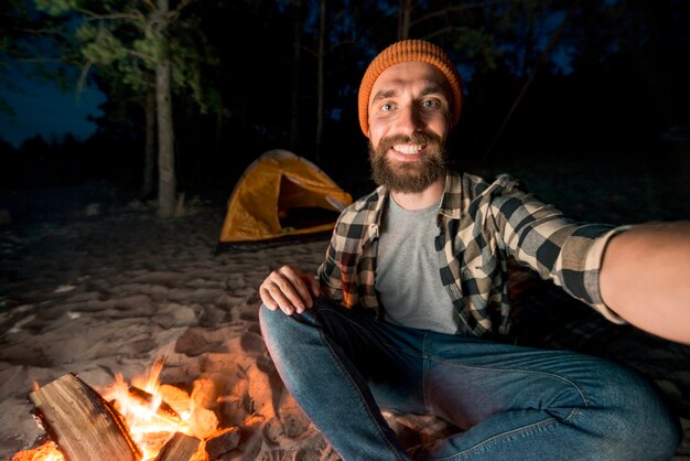 Selfie de hombre acampando junto a firecamp.
