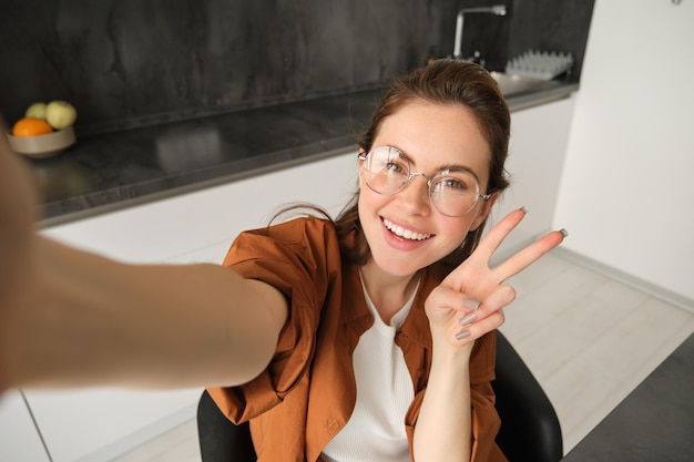 Foto gratuita selfie de una joven y elegante bloguera de estilo de vida capturando su fin de semana en casa posando para una foto