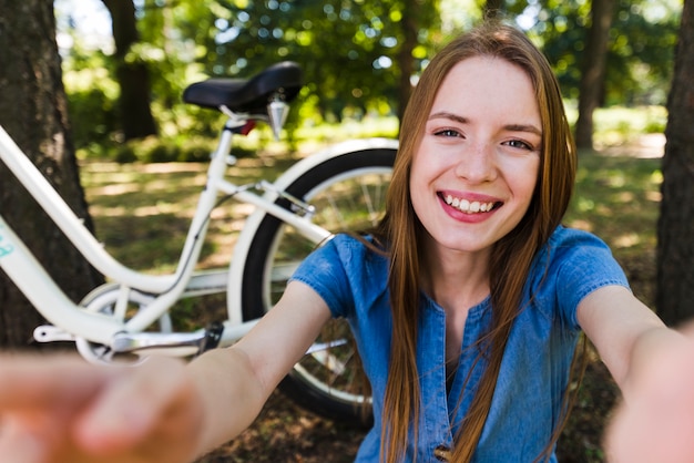 Foto gratuita selfie de una mujer sonriente junto a la bicicleta.