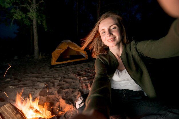 Selfie de niña acampando de noche por hoguera.