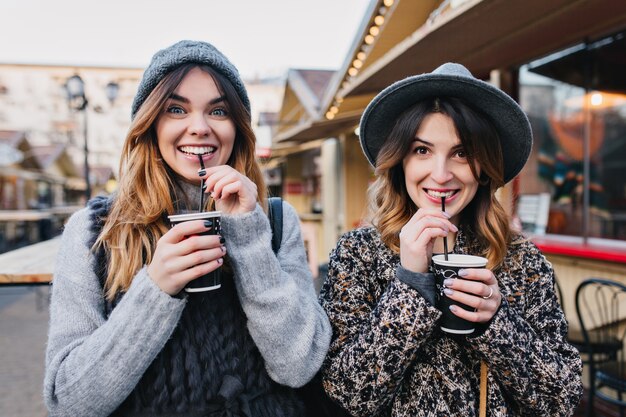 Selfie retrato de mujeres de moda alegres divirtiéndose en la calle soleada de la ciudad. Aspecto elegante, divertirse, viajar con amigos, sonreír, expresar verdaderas emociones positivas.