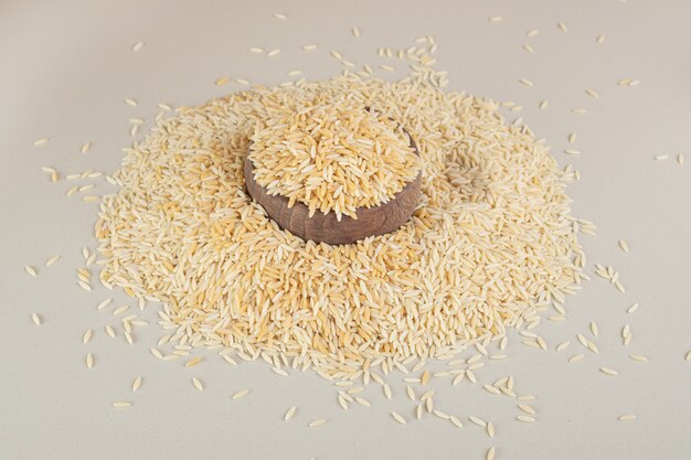 Semillas de arroz amarillo en una taza de madera sobre hormigón.