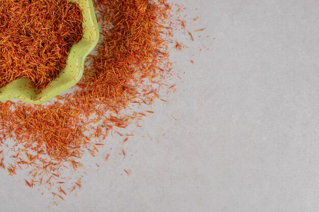 Semillas de azafrán rojo en una taza en el suelo.
