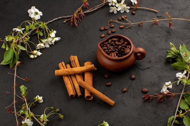 semillas de café canela vista superior junto con flores blancas en el piso oscuro