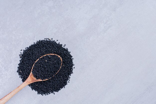 Semillas de comino negro en una cuchara de madera. Foto de alta calidad