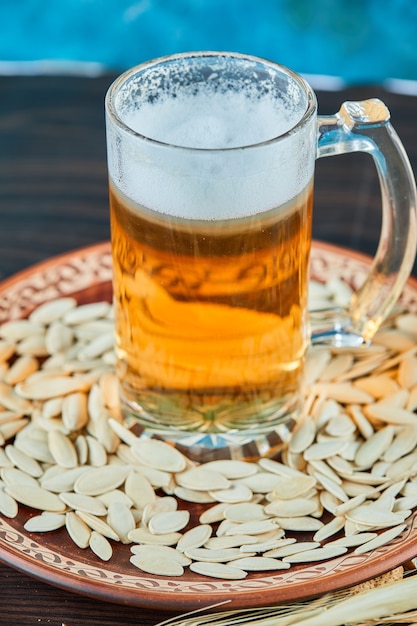 Foto gratuita semillas de girasol y un vaso de cerveza en la mesa oscura.