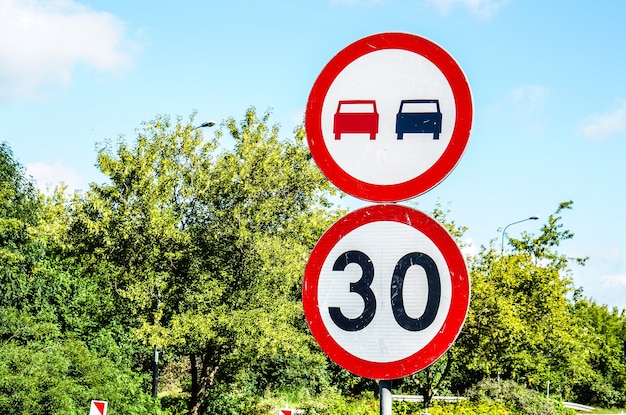 Señal que indica el límite de velocidad de treinta y no adelantar contra árboles verdes