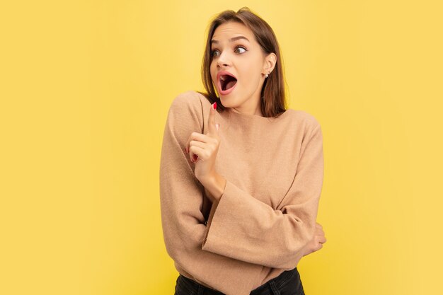 Señalando. Retrato de joven mujer caucásica aislada en amarillo