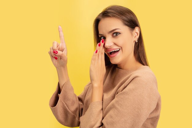 Señalando. Retrato de joven mujer caucásica aislada en amarillo