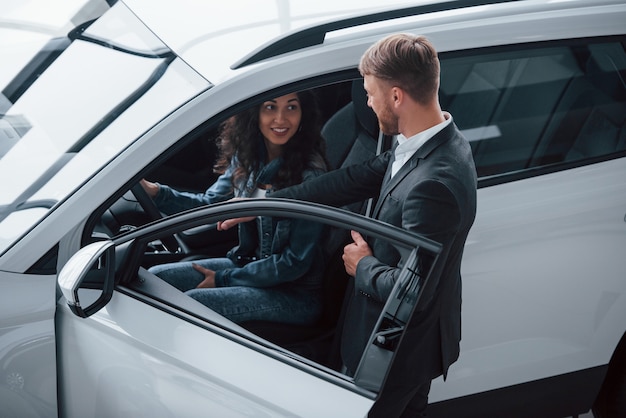 Sencillo y cómodo. Clienta y empresario barbudo con estilo moderno en el salón del automóvil