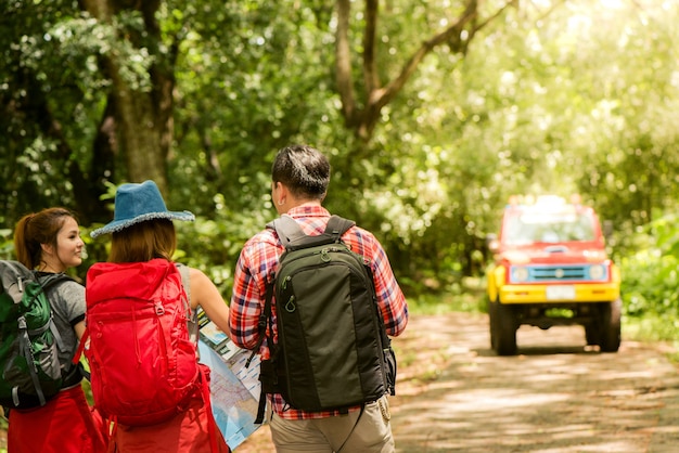 Foto gratuita senderismo - excursionistas mirando el mapa. pareja o amigos navegando juntos sonriendo feliz durante la excursión de camping al aire libre en el bosque. joven mujer de raza mixta asiática y el hombre.