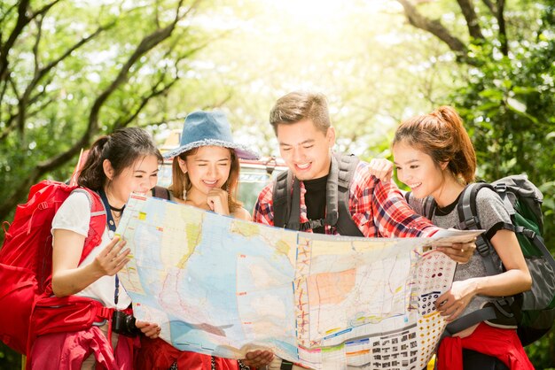 Senderismo - excursionistas mirando el mapa. Pareja o amigos navegando juntos sonriendo feliz durante la excursión de camping al aire libre en el bosque. Joven mujer de raza mixta asiática y el hombre.