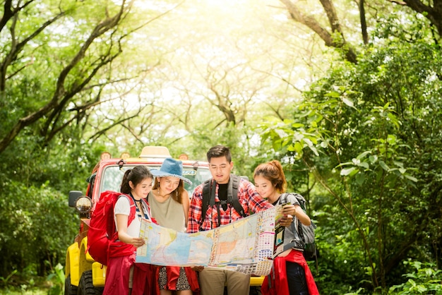 Senderismo - excursionistas mirando el mapa. Pareja o amigos navegando juntos sonriendo feliz durante la excursión de camping al aire libre en el bosque. Joven mujer de raza mixta asiática y el hombre.