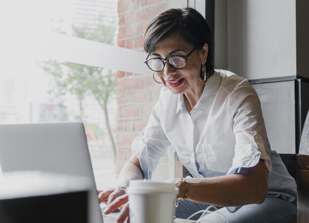 Senior feliz con anteojos trabajando en la computadora portátil