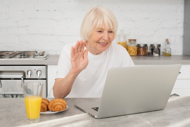 Foto gratuita senior feliz con una computadora portátil y un vaso con jugo