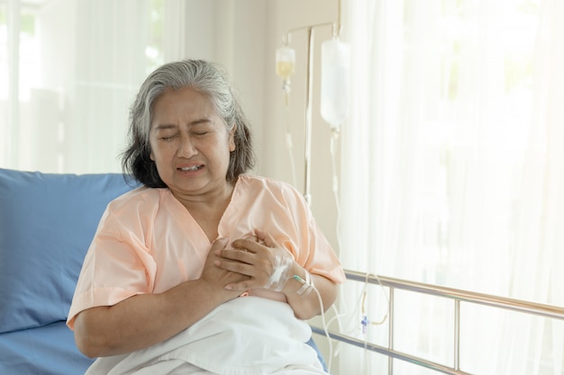 Senior femenino asiático que sufre de un fuerte dolor en el pecho ataque al corazón en casa - enfermedad cardíaca mayor