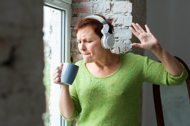 Senior femenino cantando en la taza de café