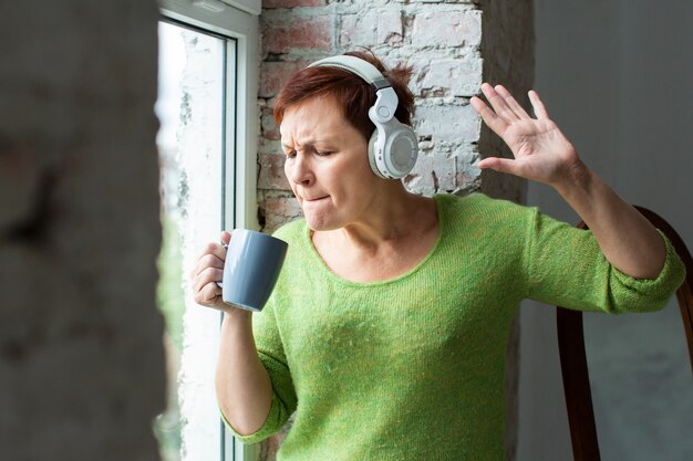 Senior femenino cantando en la taza de café