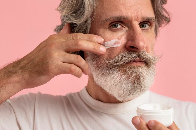 Senior hombre con barba, aplicar la crema