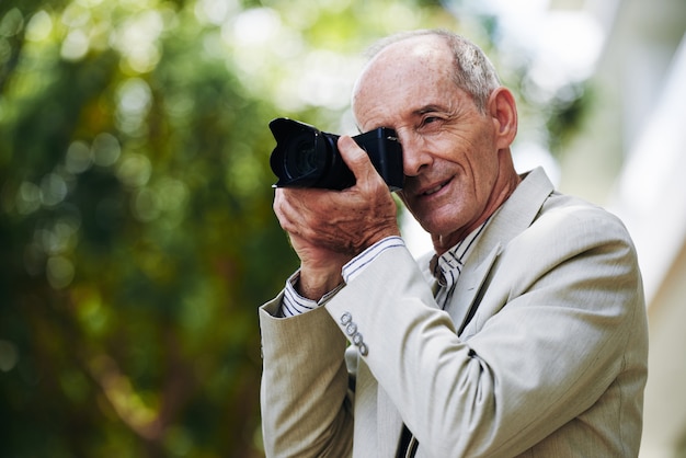 Senior hombre caucásico en traje tomando fotos en la calle