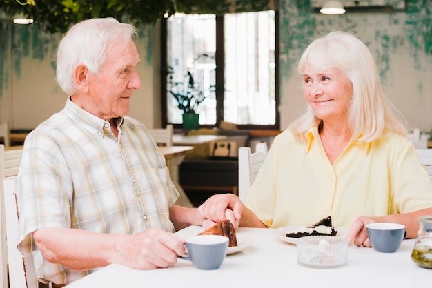 Foto gratuita senior hombre y comer desiertos bebiendo bebidas calientes