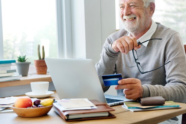 Senior hombre de compras en línea con una tarjeta de crédito