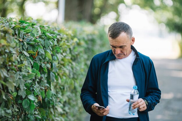 Senior hombre comprobando móvil al aire libre