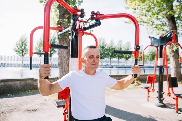 Senior hombre ejercitando los músculos de los brazos