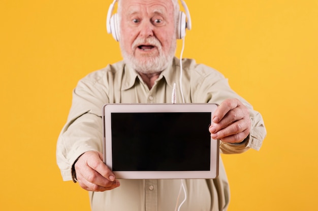 Foto gratuita senior hombre escuchando música en tableta