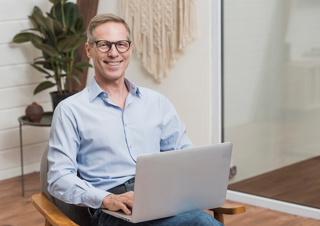 Senior hombre con gafas sosteniendo una laptop