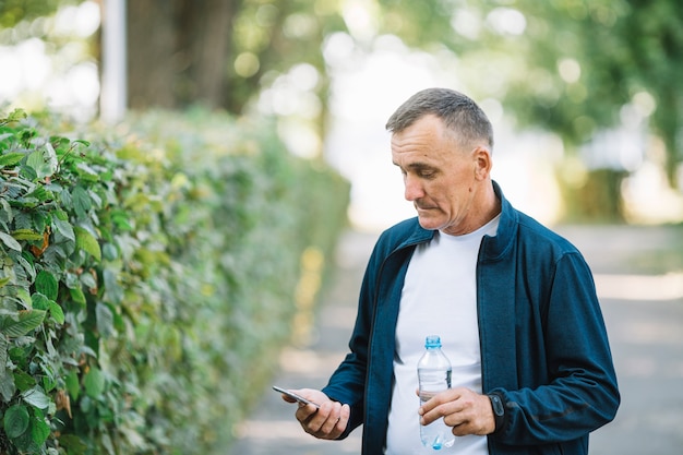 Foto gratuita senior hombre mirando al aire libre móvil