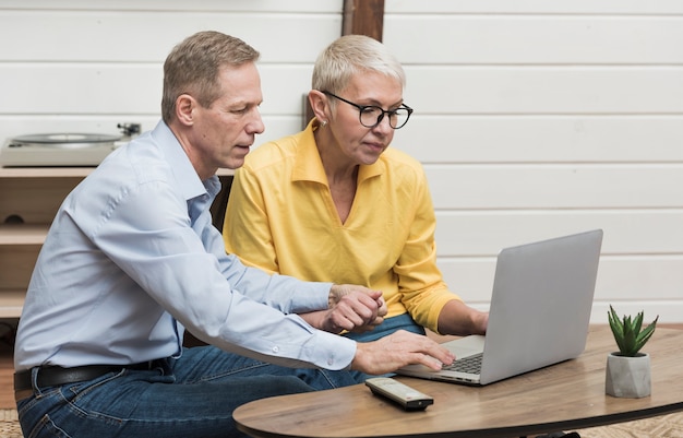 Foto gratuita senior hombre mirando a través de su computadora portátil junto a su esposa