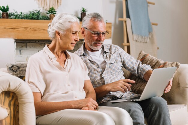 Senior hombre mostrando algo en la computadora portátil a su esposa