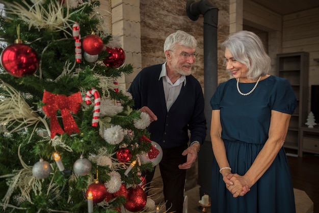 Senior hombre y mujer junto al árbol de navidad