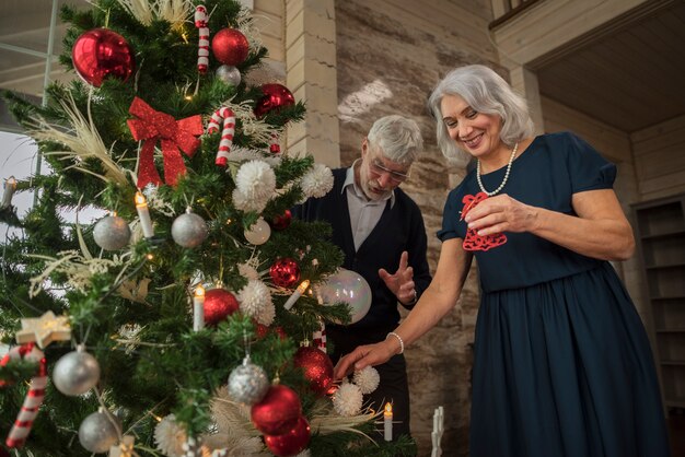 Senior hombre y mujer junto al árbol de navidad