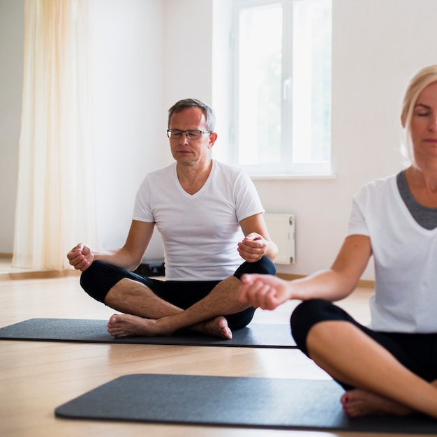 Foto gratuita senior hombre y mujer meditando sobre colchonetas de yoga