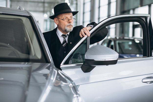 Senior hombre en una sala de exposición de automóviles elegir un automóvil