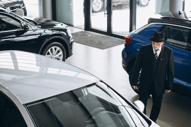 Senior hombre en una sala de exposición de automóviles elegir un automóvil