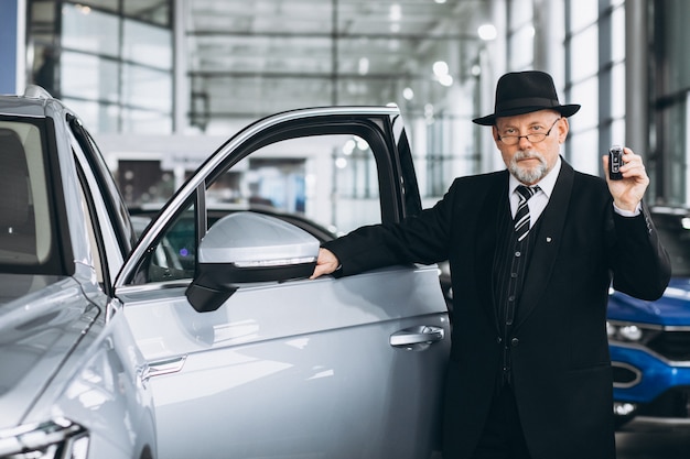 Senior hombre en una sala de exposición de automóviles elegir un automóvil