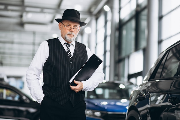 Senior hombre en una sala de exposición de automóviles elegir un automóvil