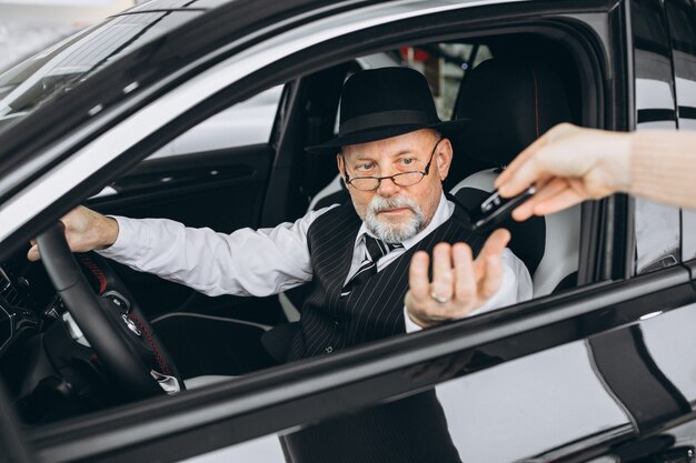 Senior hombre sentado dentro de un auto