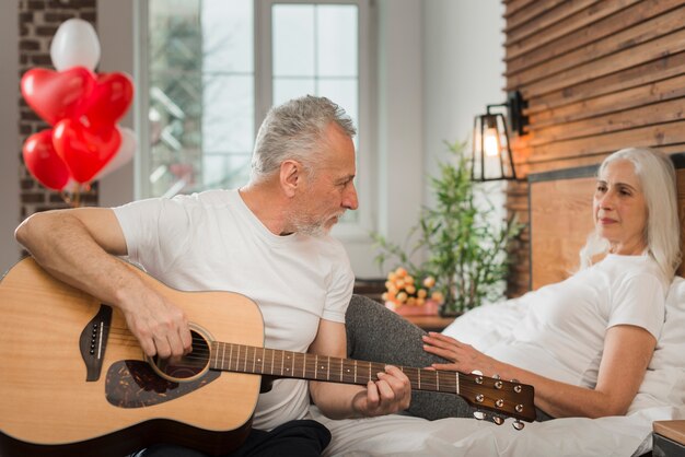 Senior hombre serenata esposa en el día de San Valentín