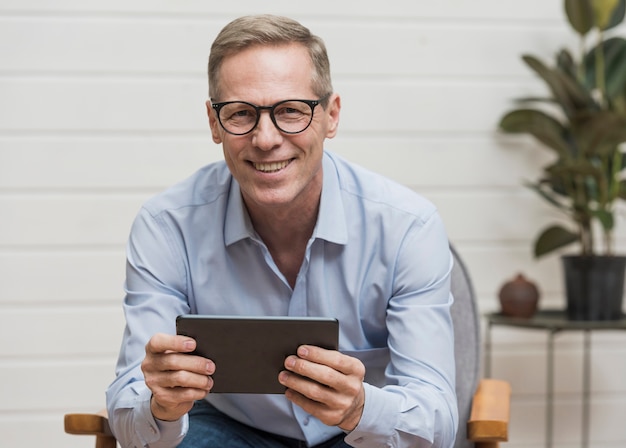 Senior hombre sonriente sosteniendo su tableta